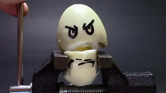 鸡蛋上画着悲伤的脸，被压在金属虎钳的手臂之间，关于压力和健康相关问题的概念性镜头