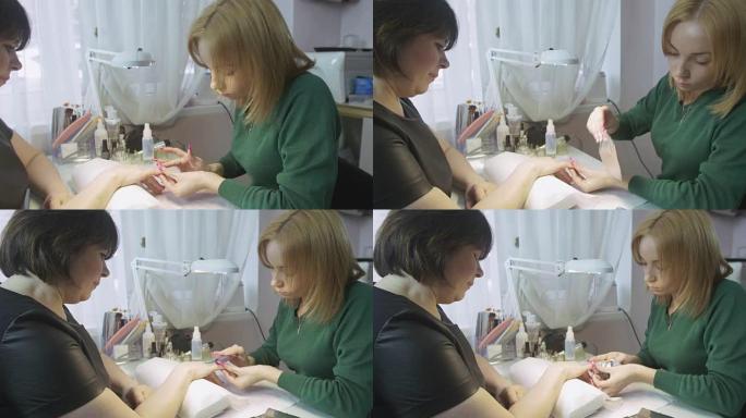 美甲师将化妆棉和箔纸放在美容院的成年女性的指甲上。虫胶盖的拆卸