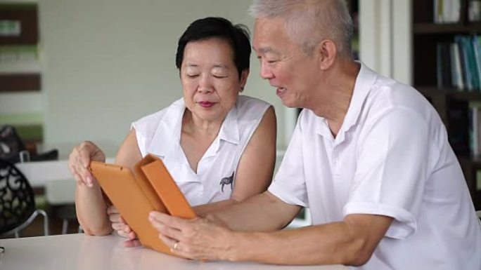 亚洲老年夫妇在小图书馆的平板电脑上一起阅读新闻。学习和学习理念