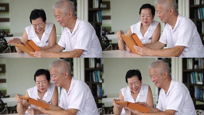 亚洲老年夫妇在小图书馆的平板电脑上一起阅读新闻。学习和学习理念