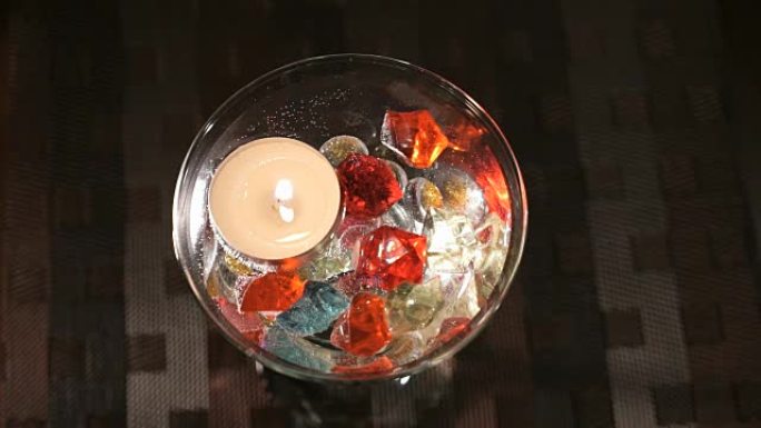 蜡烛在散布着宝石的玻璃杯中燃烧