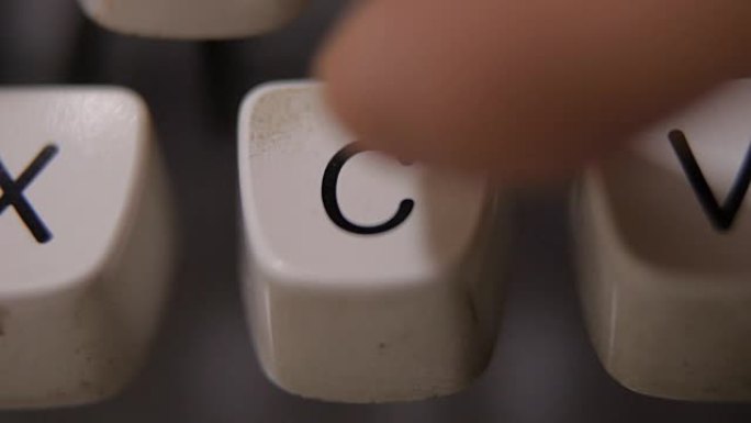 老式复古打字机上的手指打字字母C。