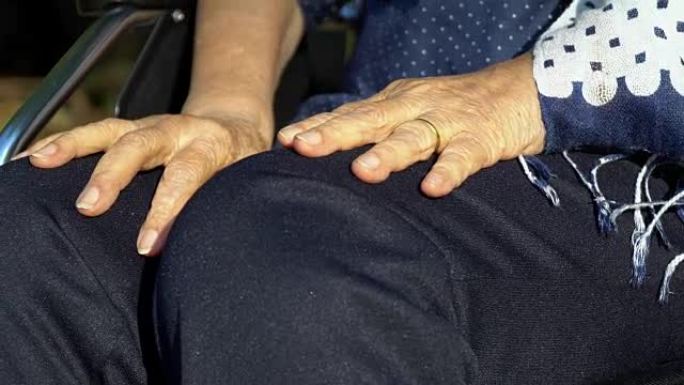 老年妇女把手放在轮椅上。
