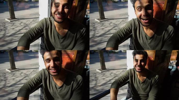 英俊的阿拉伯男人在咖啡馆微笑着眨眨眼