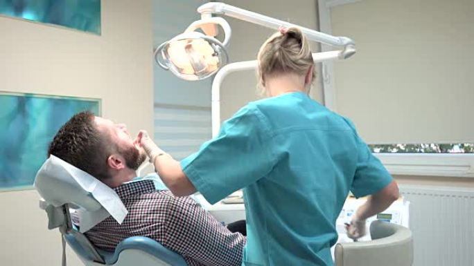 女牙医钻牙齿，看着镜头。滑块镜头，左。