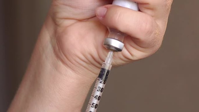 女孩在注射器里拿起胰岛素，特写。