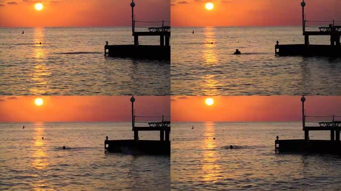 海上美丽的日落。盖伊从码头跳入地中海的剪影