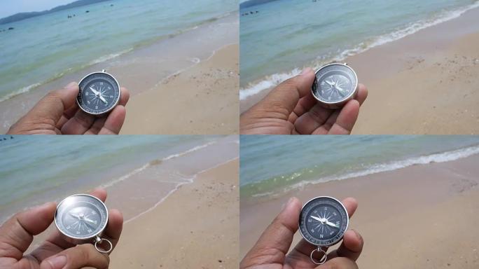 mand的近距离拍摄手在沙滩上拿着指南针，具有自然的海洋和风的环境声音