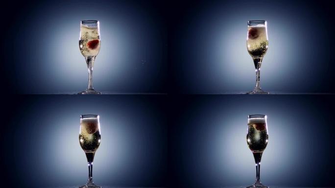 在玻璃杯中，香槟酒落下新鲜的草莓，慢动作