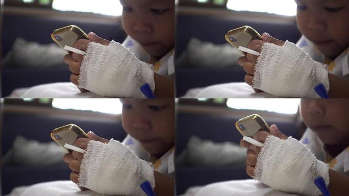 婴儿女儿在病床医院使用智能手机的特写镜头。年轻患者的放松时间。在治疗室实时拍摄。