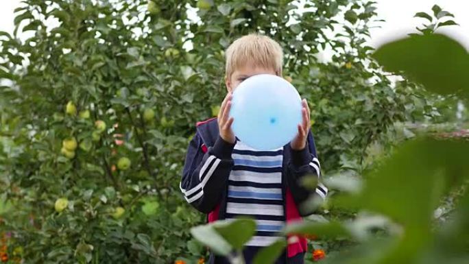 花园里的孩子给蓝色气球充气