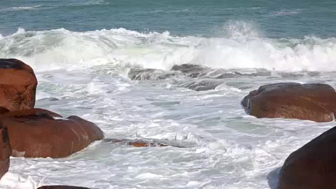 海浪在沿海粉色石头巨石上破碎。