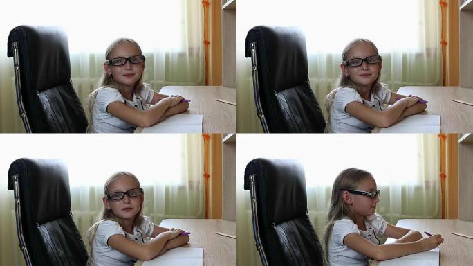 年轻的白人女孩戴着眼镜坐在桌子旁边的椅子上。室内近距离观看漂亮的女孩在眼镜。白人女孩用钢笔在纸上写东