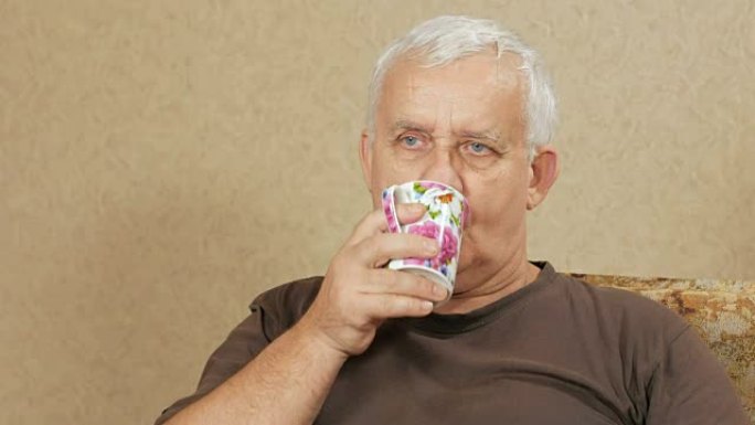 那个从杯子里喝咖啡，看着镜头的男人。辛苦一天后，他在家躺在沙发上放松。度假屋概念