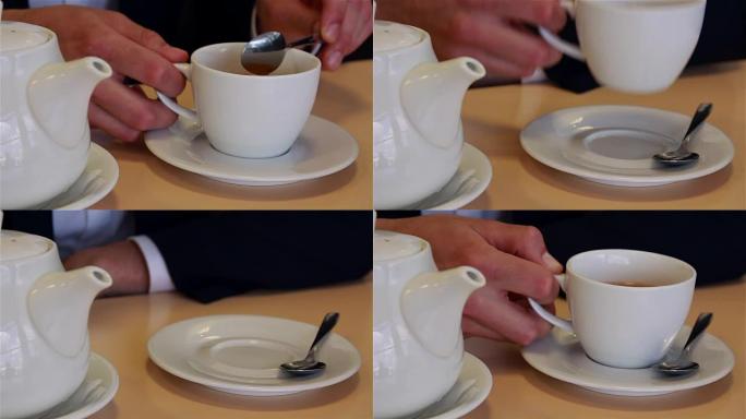 男性双手合拢将茶倒入杯子和汤匙