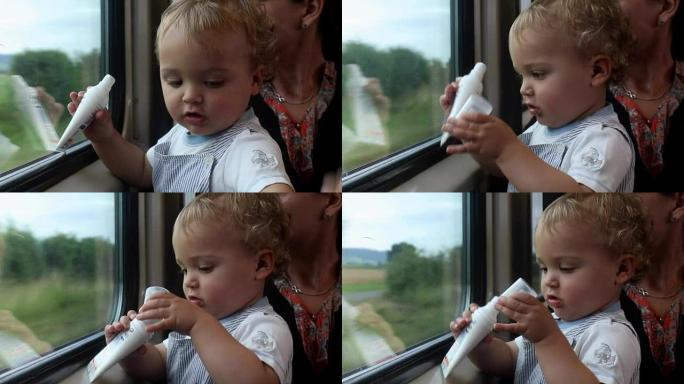 婴儿和母亲坐火车旅行。婴儿在打时间的同时玩物体