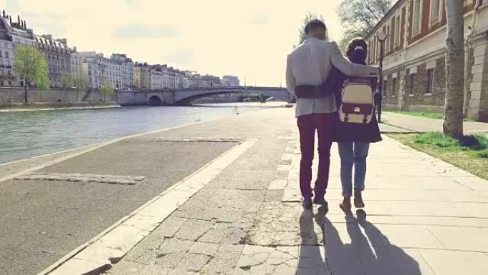 一对年轻夫妇在巴黎圣母院附近的塞纳河岸边浪漫地散步
