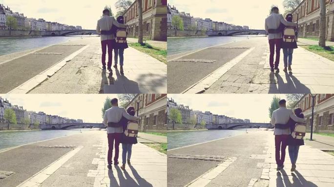 一对年轻夫妇在巴黎圣母院附近的塞纳河岸边浪漫地散步