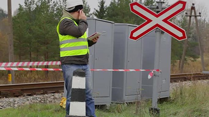 铁路工程师在警告录像带前在手机上交谈