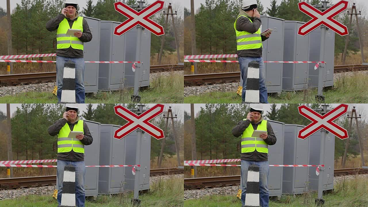 铁路工程师在警告录像带前在手机上交谈