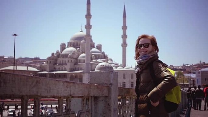 慢动作: 伊斯坦布尔的漂亮女孩看着港口和清真寺。一只大海鸥突然飞过，女孩真的很惊讶。旅行概念