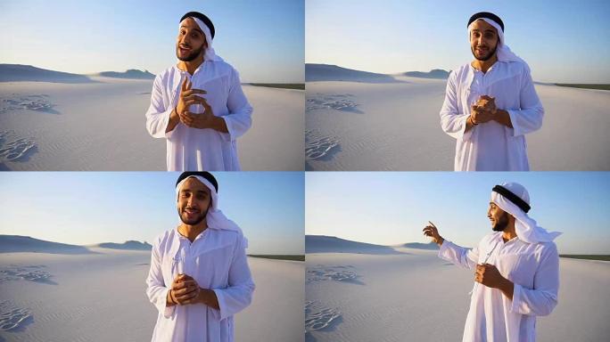 有魅力的阿拉伯男导游站在广阔的沙漠中谈论着旅行的优点，看着相机