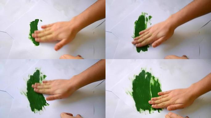 绿色油漆通过白纸涂抹双手