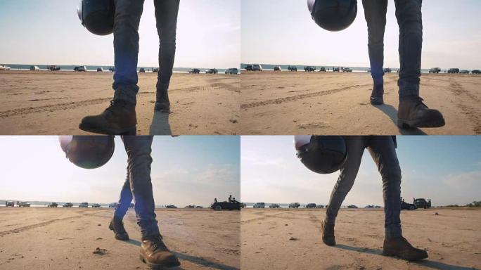 日落时摩托车手戴着头盔在沙漠中行走的特写镜头