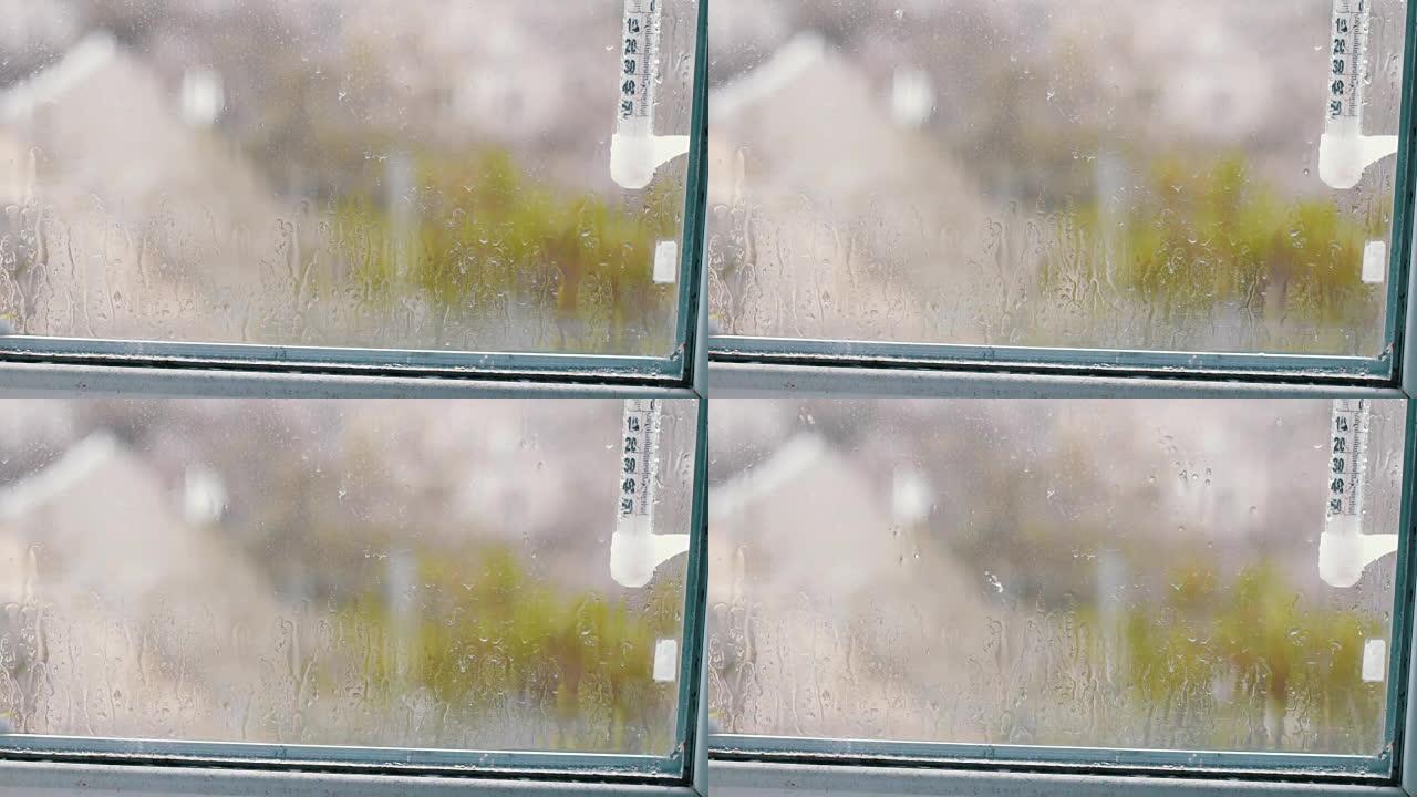 雨滴顺着窗户上的玻璃流下。显示窗外温度的温度计
