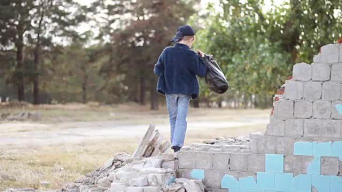 一个带着苹果和袋子的孤儿男孩走过被毁房屋的废墟