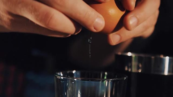 调酒师用手制动鸡蛋并将其放入玻璃杯中制作鸡尾酒