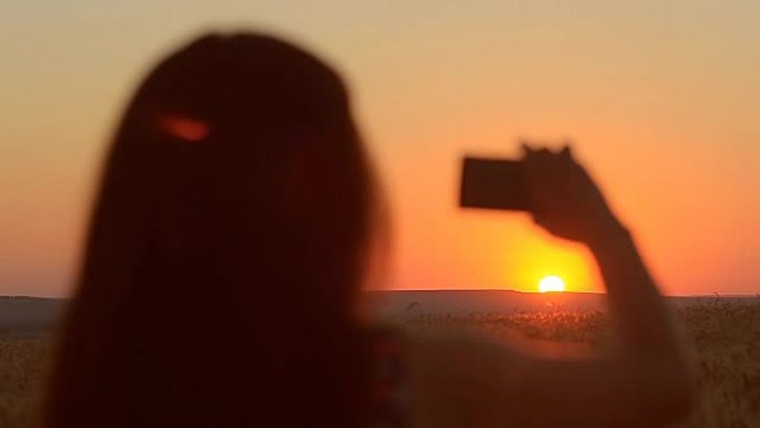 女孩带着手机在日落的夜晚风景图片日落在手机上美丽。