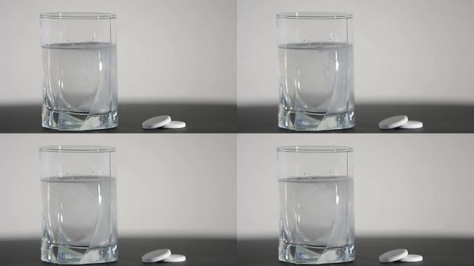 阿司匹林或泡腾药丸滴入白色背景的一杯水中。