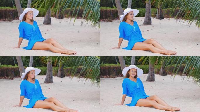 海滩度假。穿着遮阳帽和比基尼的性感美女站在那里，双臂举到头，在炎热的夏日欣赏海滩海洋的景色。照片来自