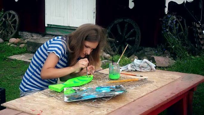 年轻女子在院子里的木桌上画鱼装饰