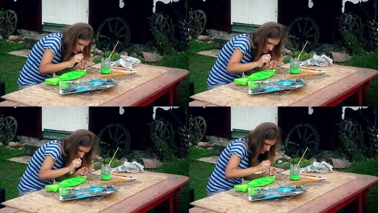 年轻女子在院子里的木桌上画鱼装饰