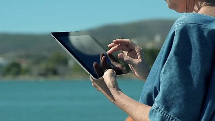在海边使用平板电脑的抽象特写女人