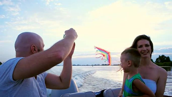 父母陪孩子玩耍，一家人放风筝坐在船上，乘着船速，一个快乐的孩子大笑，母亲，父亲和儿子度过时光