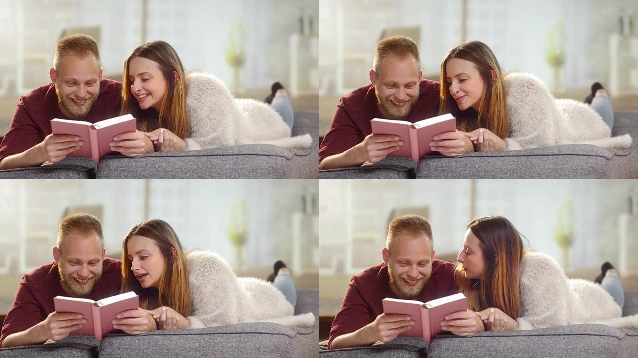 年轻可爱的夫妇躺在沙发上读一本有趣的书