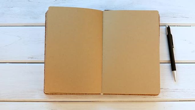 白色木制桌子上的男性手关闭日记本，俯视图和头顶镜头用于空白模板书模拟添加任何文本内容