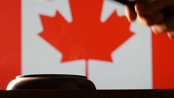 法官在加拿大法院以旗帜为背景用锤子和小木槌下达命令
