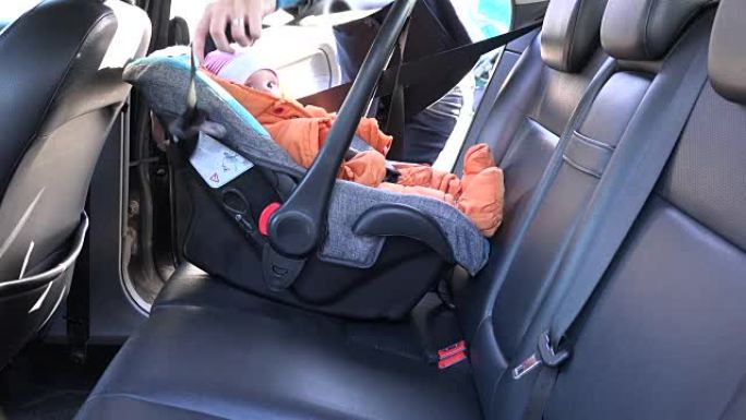 母亲解开汽车座椅上儿童的安全带。全高清