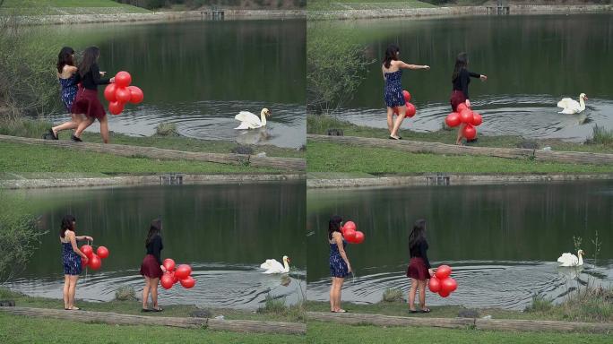 两个拿着红色气球的女孩在湖中发现天鹅