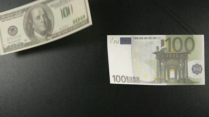 顶视图: 两张纸币躺在一张黑桌子上，然后美元飞走了