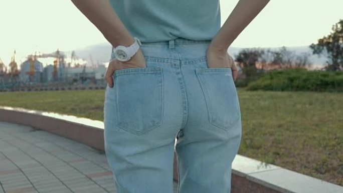 一个穿着牛仔裤和t恤等待会议的女人的特写镜头。从后面看，慢动作。