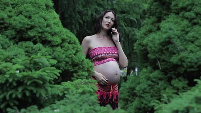 大肚子的孕妇在公园打电话。