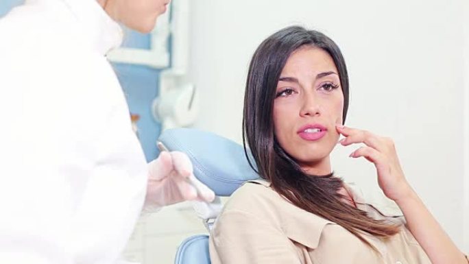 女患者与牙医交谈并显示牙齿酸痛的特写