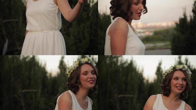 年轻漂亮的女孩，花圈和白色连衣裙在日落时在户外唱歌跳舞