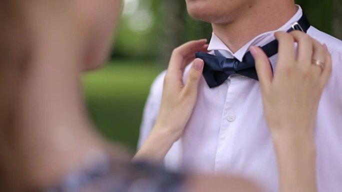 年轻的女人帮男人打领结。