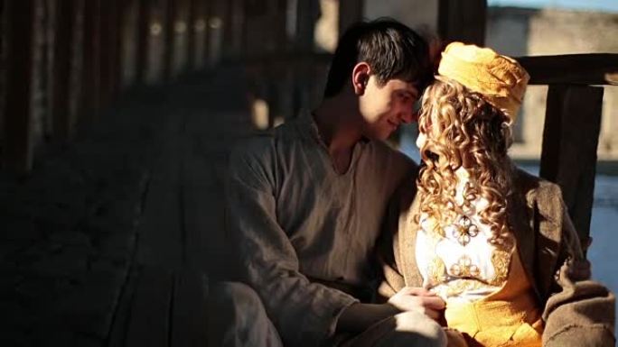 穿着传统服装的浪漫情侣在古老的中世纪城堡里轻吻